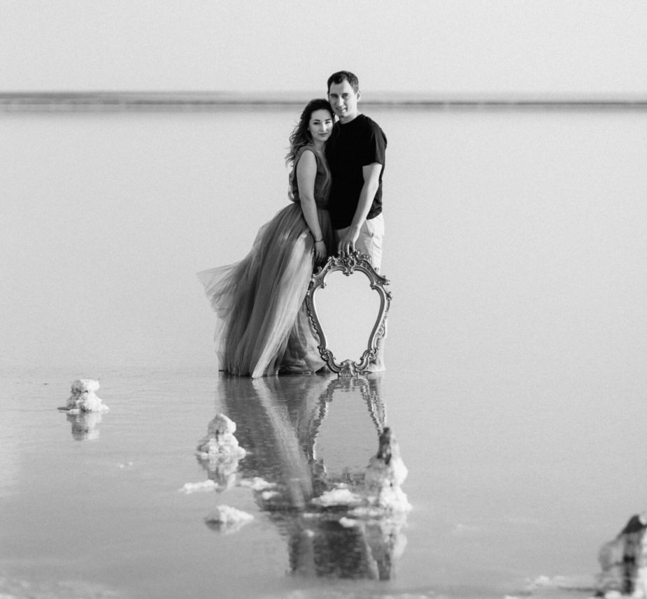 girl and a guy on the shore of a pink salt lake at sunset