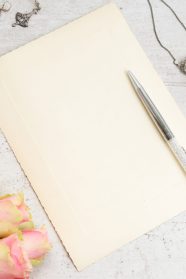 jewellery and roses on white table with copy space on aged paper note