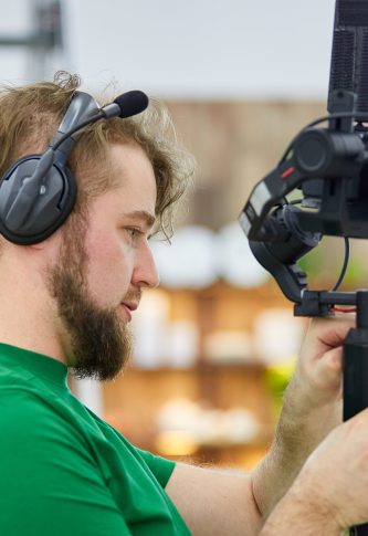 Videographer shooting a film or a television program in a studio with a professional camera, backstage.